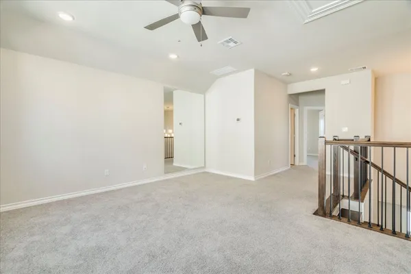 an empty room with staircase and a ceiling fan