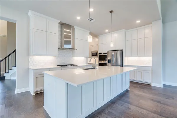 a kitchen with kitchen island a sink stainless steel appliances and white cabinets