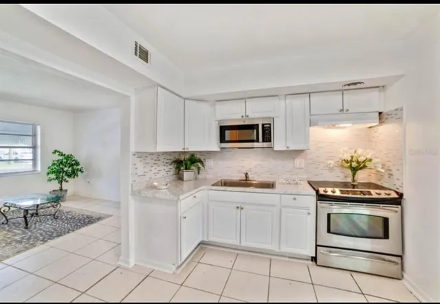 a kitchen with white cabinets a sink and appliances