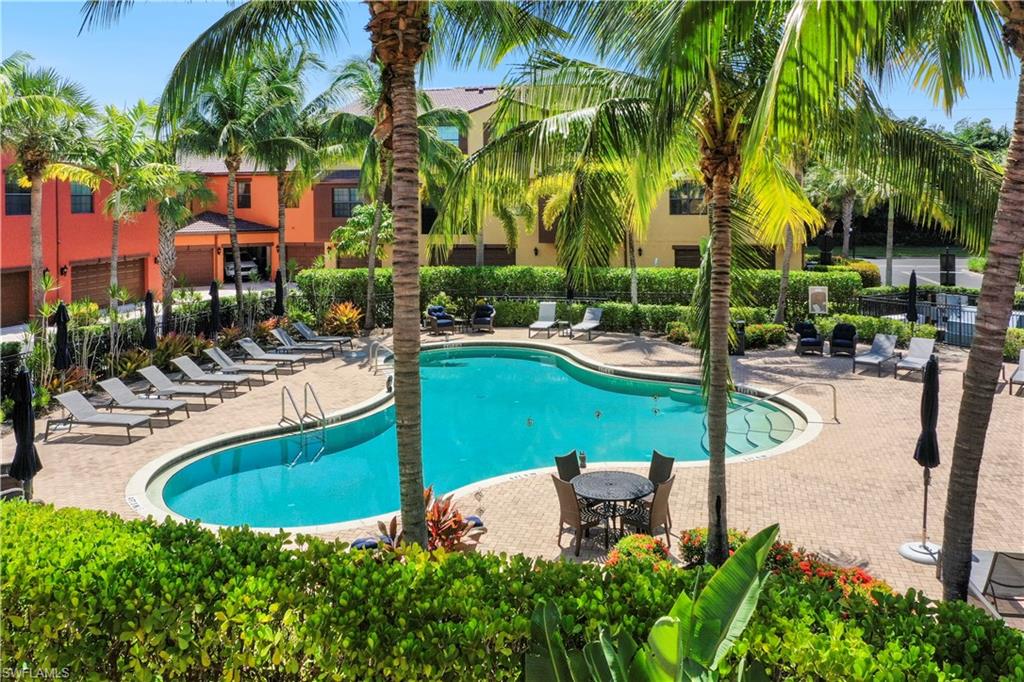 9063 Capistrano Street North, Unit 4405 Naples, FL 34113 - Photo 19 of 40 a view of a swimming pool with a table and chairs