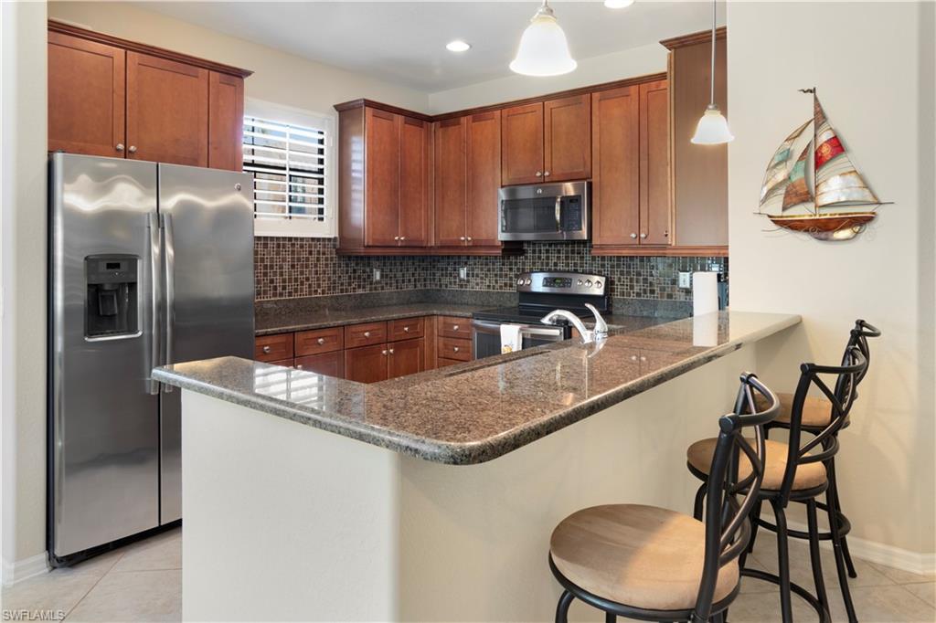 9063 Capistrano Street North, Unit 4405 Naples, FL 34113 - Photo 4 of 40 a kitchen with stainless steel appliances granite countertop a sink refrigerator and microwave