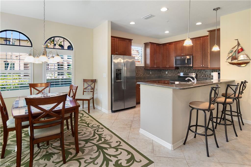 9063 Capistrano Street North, Unit 4405 Naples, FL 34113 - Photo 6 of 40 a kitchen with stainless steel appliances granite countertop a table chairs stove and cabinets