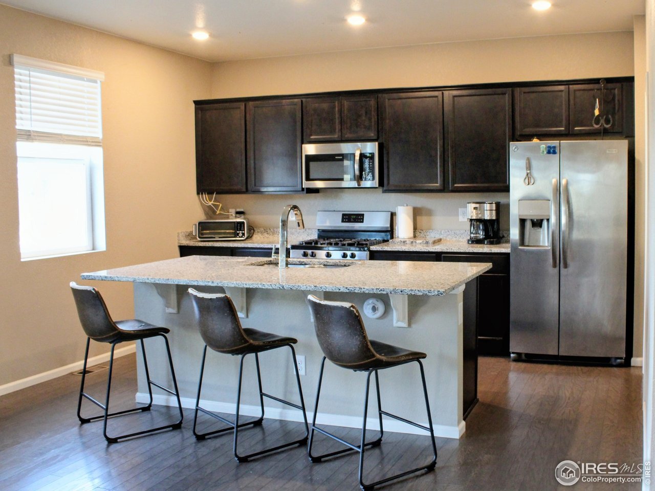 415 3rd Street Severance, CO 80550 - Photo 7 of 25 a kitchen with stainless steel appliances a table chairs refrigerator and microwave