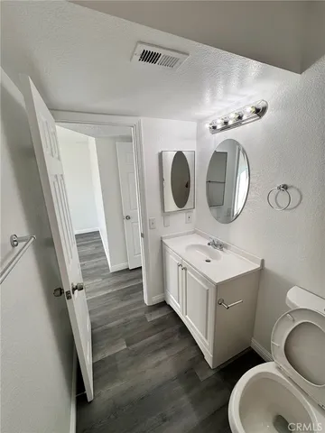 a bathroom with a toilet sink vanity granite and mirror