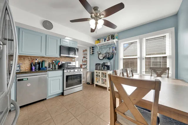 a kitchen with granite countertop a stove a sink dishwasher a dining table and chairs with wooden floor