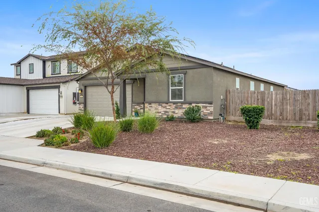 a front view of a house with plants and a tree