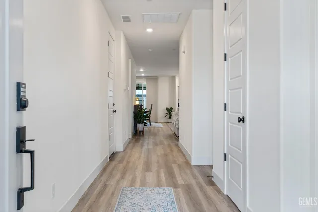 a view of a hallway with wooden floor and a bathroom