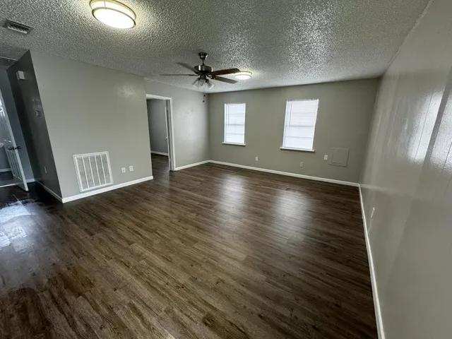an empty room with wooden floor and windows