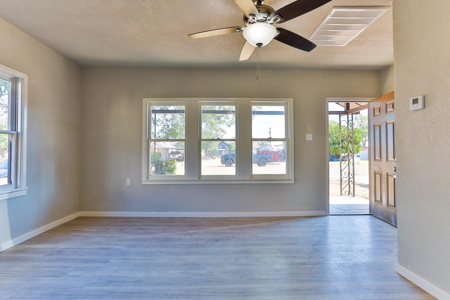 435 West Lynn Street Slaton, TX 79364 - Photo 3 of 22 a view of an empty room with wooden floor and a window