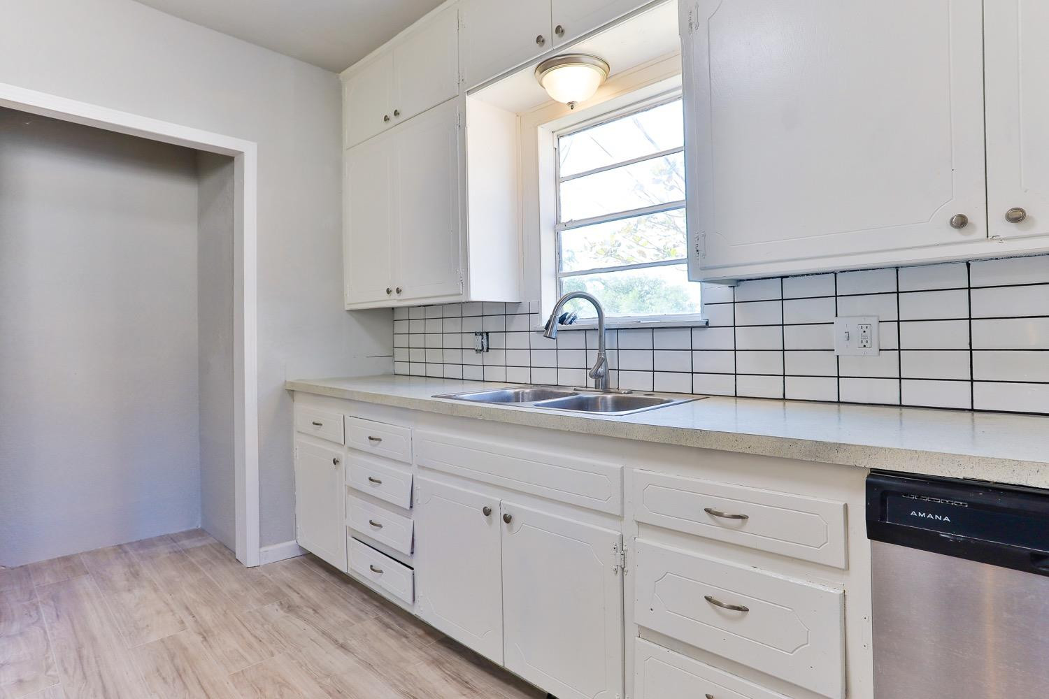 435 West Lynn Street Slaton, TX 79364 - Photo 5 of 22 a kitchen with white cabinets a sink and dishwasher