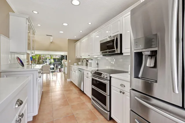 a kitchen with stainless steel appliances granite countertop a refrigerator a stove top oven a sink dishwasher and white cabinets with wooden floor