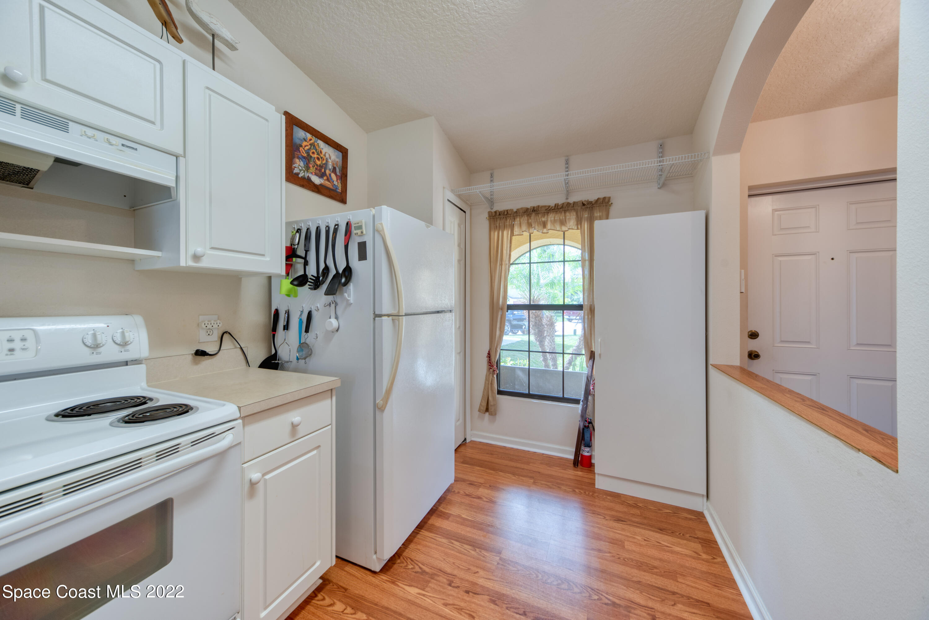 995 Luminary Circle, Unit 103 Melbourne, FL 32901 - Photo 9 of 27 a view of a kitchen with fridge and wooden floor