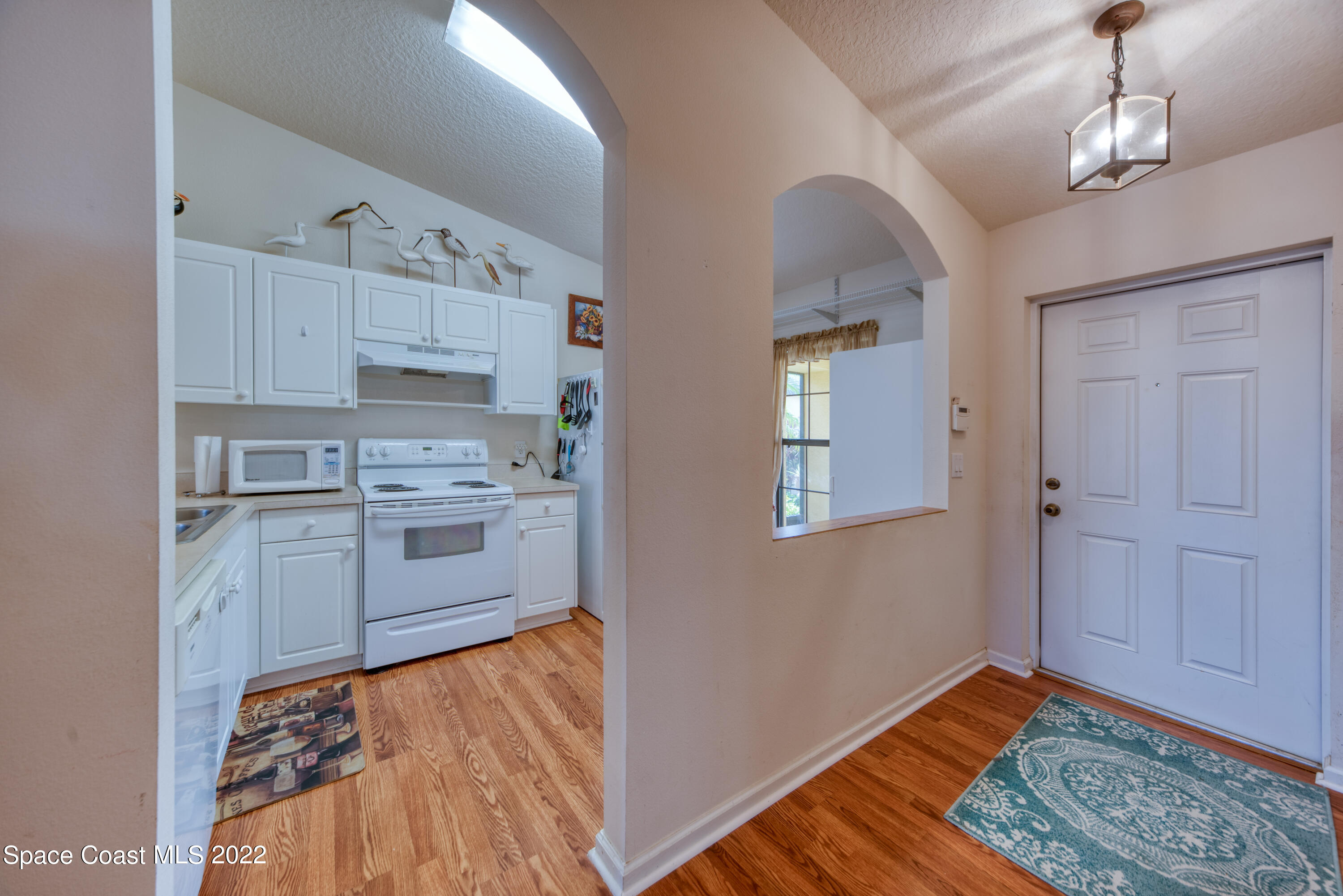 995 Luminary Circle, Unit 103 Melbourne, FL 32901 - Photo 10 of 27 a kitchen with kitchen island white cabinets and wooden floor