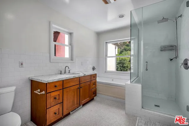 a bathroom with a granite countertop sink a toilet and shower