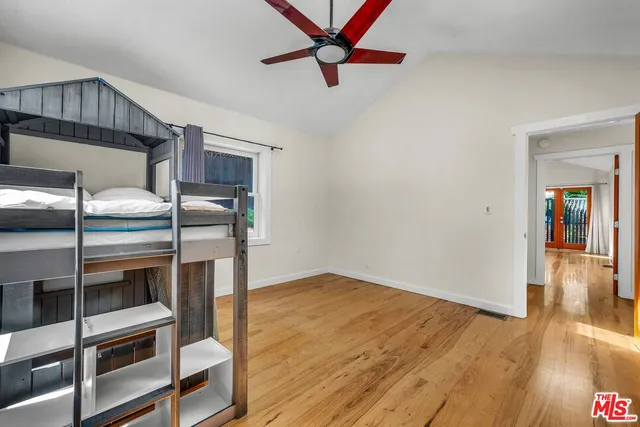 an empty room with wooden floor ceiling fan and windows