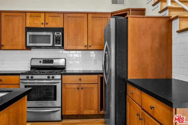 a kitchen with stainless steel appliances granite countertop a stove microwave and refrigerator