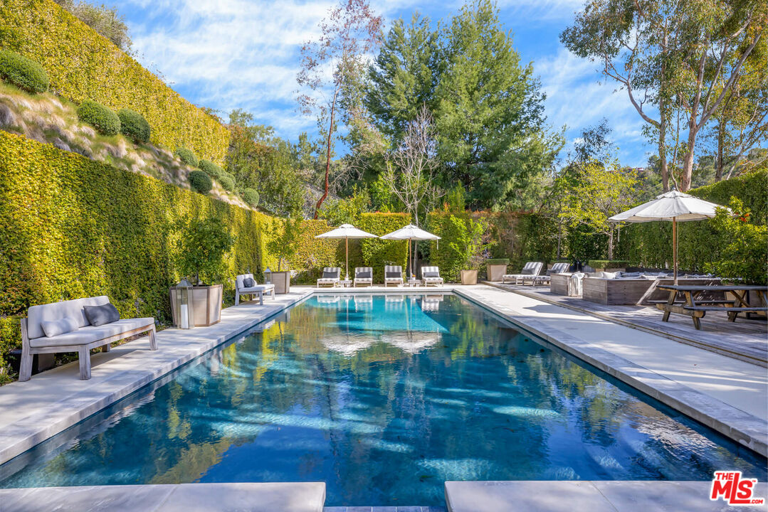 9779 Oak Pass Road Beverly Hills, CA 90210 - Photo 30 of 43 a view of a swimming pool with chairs and an umbrella