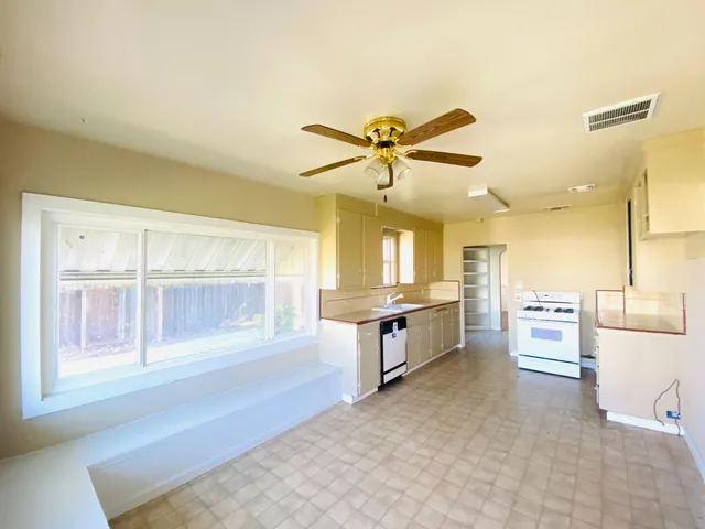 a large white kitchen with a large window a sink and stainless steel appliances