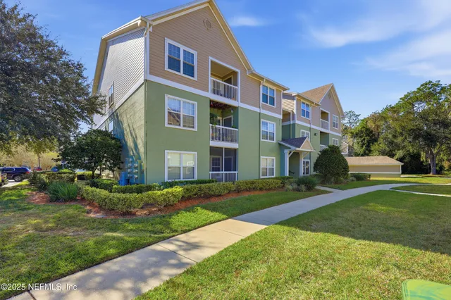 a view of a building next to a yard with big trees