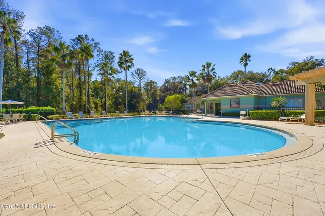 a view of swimming pool with outdoor seating and trees in the background