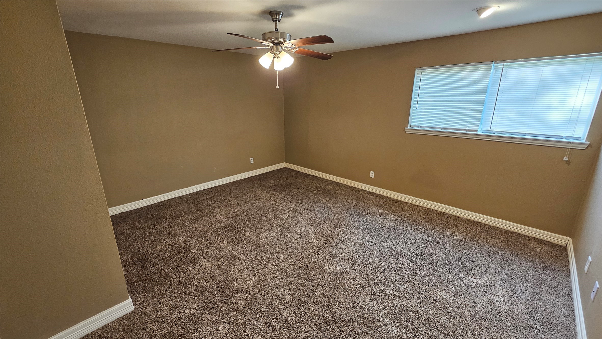 14807 Spring Lake Drive Houston, TX 77070 - Photo 17 of 21 an empty room with a chandelier fan and a window