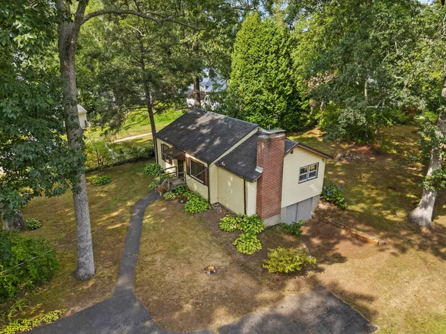 an aerial view of a residential houses with outdoor space and trees all around