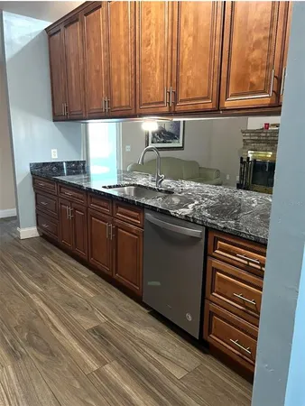 a kitchen with granite countertop wooden cabinets a sink and dishwasher