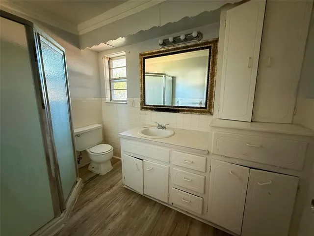 an empty room with wooden floor cabinet and windows