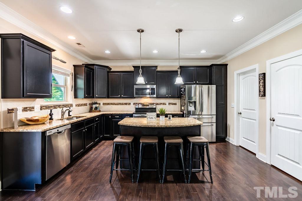 3578 Eastern Branch Road Raleigh, NC 27610 - Photo 5 of 24 a kitchen with kitchen island granite countertop a sink a stove a refrigerator and island with wooden floor