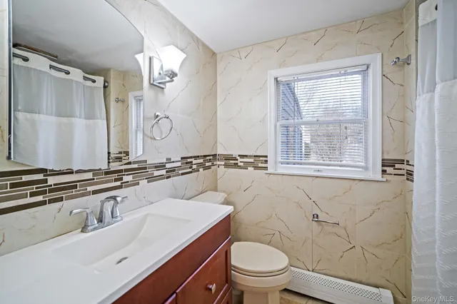 a bathroom with a granite countertop sink a toilet and a mirror