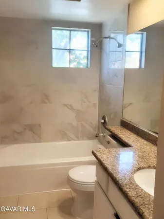 a bathroom with a granite countertop toilet a sink and bathtub