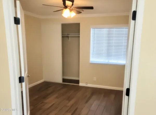 an empty room with wooden floor closet and windows