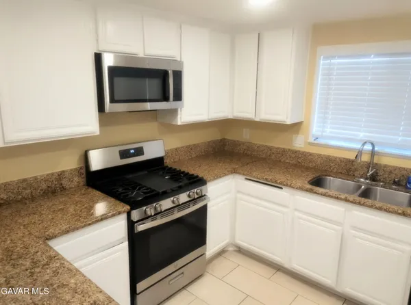 a kitchen with granite countertop white cabinets and appliances