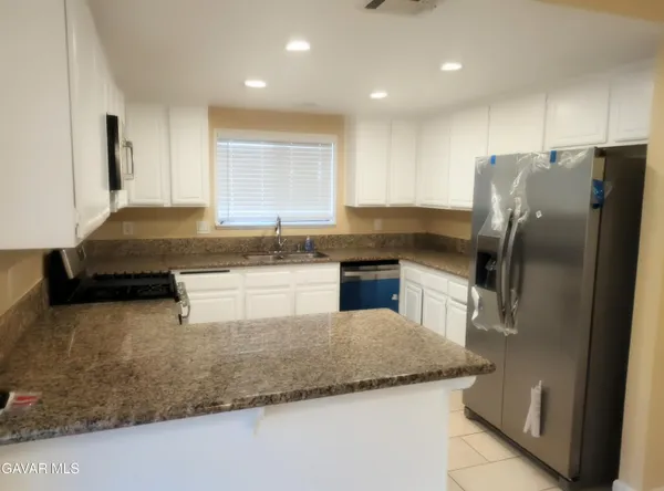 a kitchen with granite countertop stainless steel appliances a sink a counter top space and cabinets