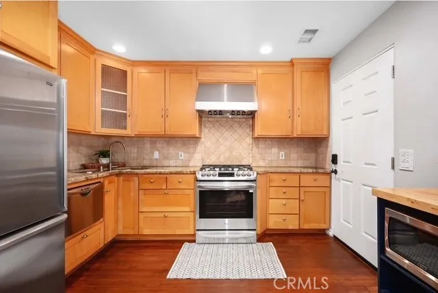 a kitchen with stainless steel appliances granite countertop a stove sink and cabinets