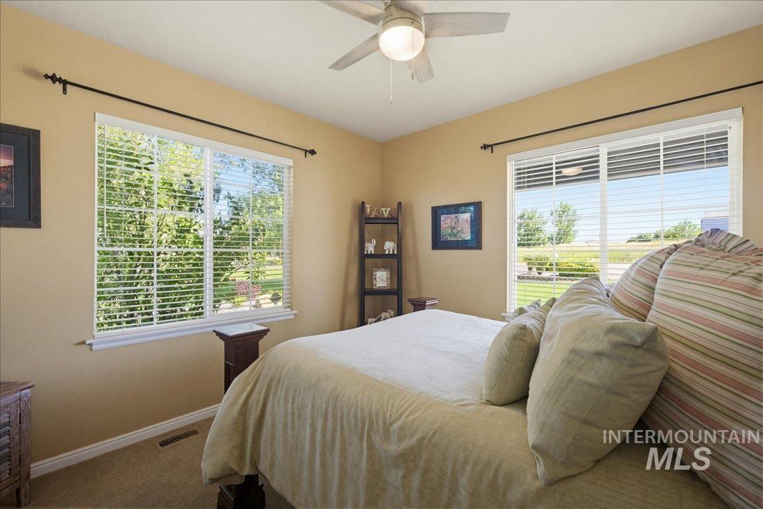 24623 Falcon Lane Caldwell, ID 83607 - Photo 13 of 40 Spacious bedroom featuring neutral wall tones, plush carpeting, a multi-pane window with horizontal blinds, and a sliding glass door providing outdoor access