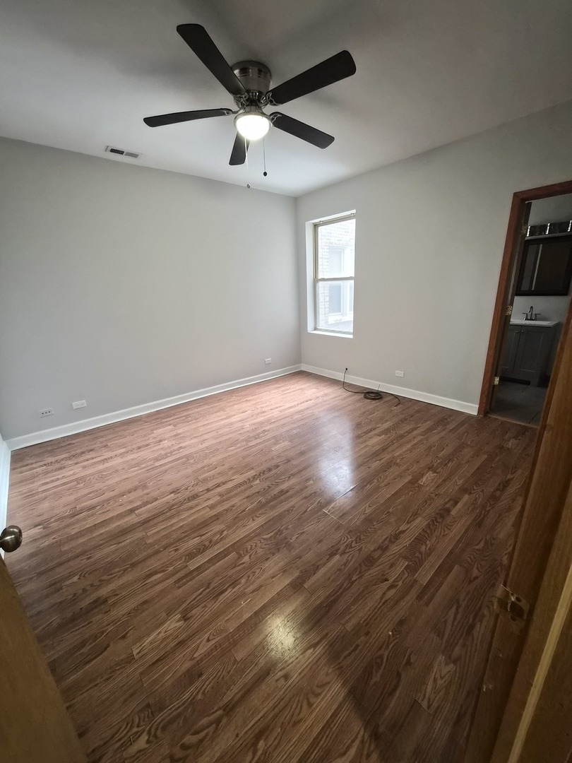 4828 South Indiana Avenue, Unit 201 Chicago, IL 60615 - Photo 11 of 17 an empty room with wooden floor fan and windows