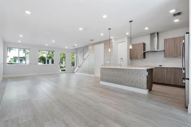 a large hall with stainless steel appliances kitchen island a large counter top and a wooden floors
