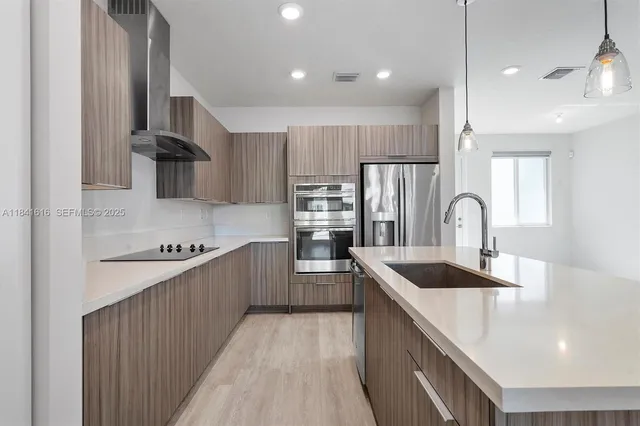 a kitchen with kitchen island stainless steel appliances a sink stove and refrigerator
