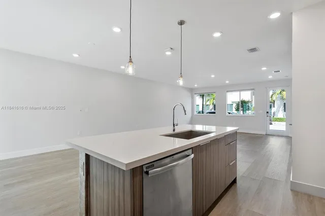 a kitchen with a sink a center island a counter space and a refrigerator