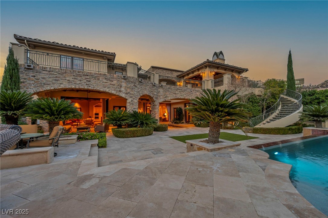 1793 Anelli Court Henderson, NV 89012 - Photo 14 of 47 Back of house at dusk featuring an outdoor pool, stairway, a patio area, a balcony, and outdoor lounge area