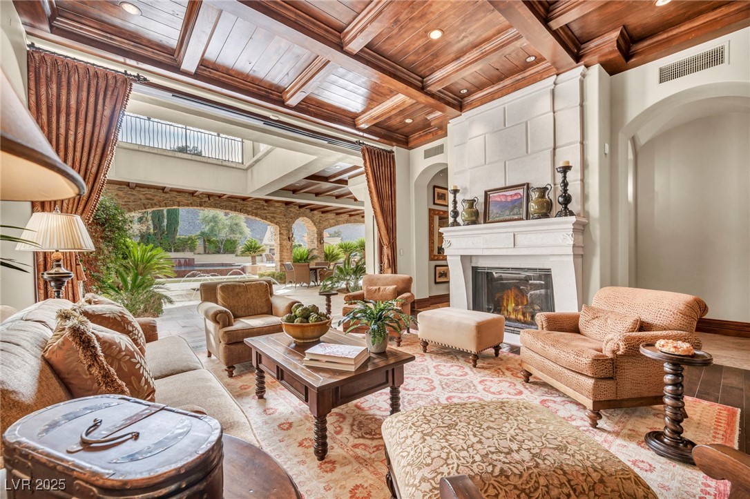 1793 Anelli Court Henderson, NV 89012 - Photo 19 of 47 Living room with a wood ceiling with exposed beams, coffered ceiling, a large fireplace, arched walkways, and ornamental molding