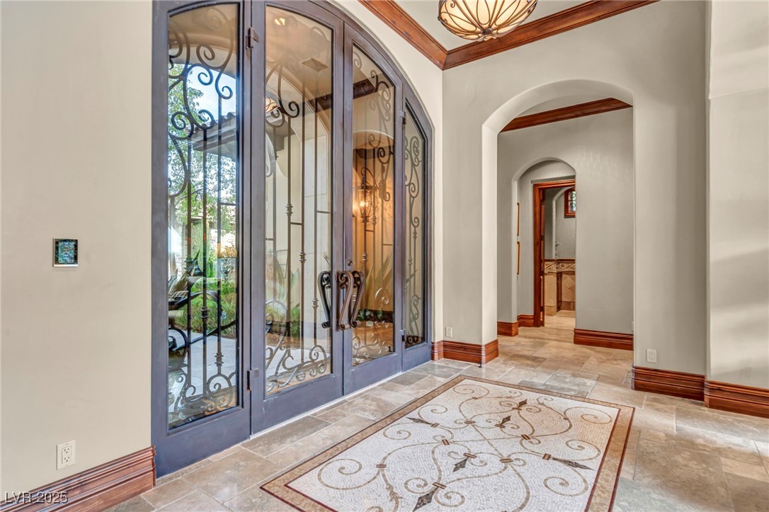 1793 Anelli Court Henderson, NV 89012 - Photo 7 of 47 Foyer with ornamental molding, stone tile flooring, arched walkways, and french doors