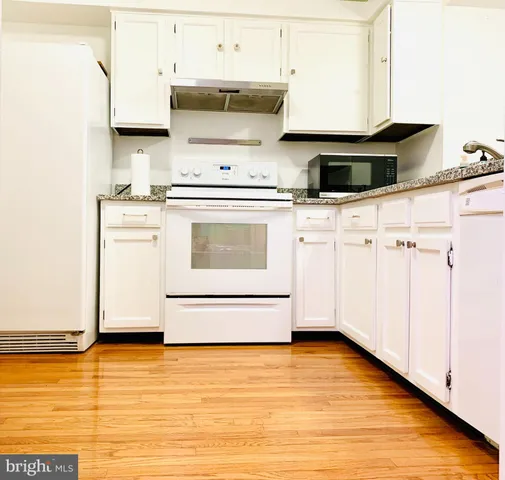 a kitchen with stainless steel appliances granite countertop a stove a sink and white cabinets