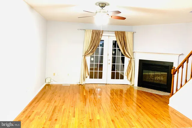 a view of an empty room with wooden floor and a chandelier fan