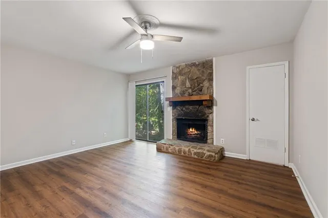 a view of an empty room with wooden floor fireplace and a window