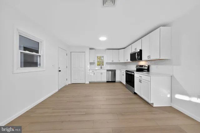 a view of an empty room with wooden floor and closet