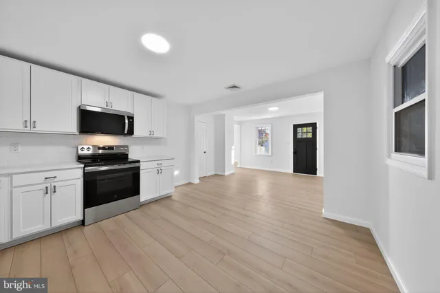 a kitchen with stainless steel appliances kitchen island granite countertop a dining table chairs and a refrigerator