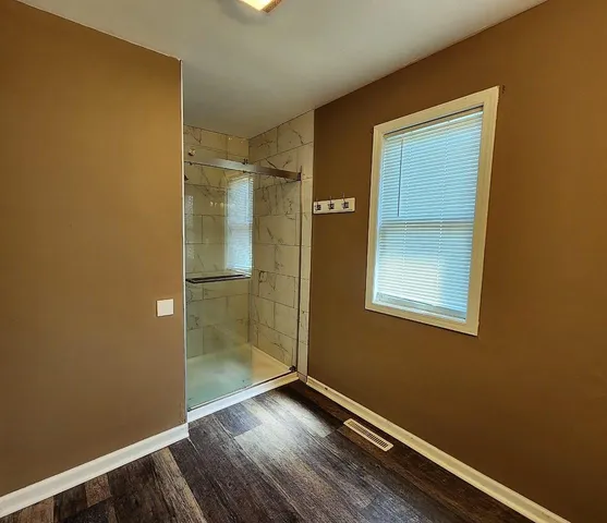an empty room with wooden floor closet and windows