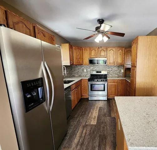 a kitchen with stainless steel appliances a refrigerator a stove a sink a washer and dishwasher with wooden floor